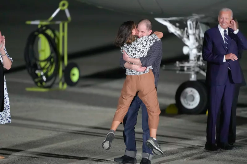 Reporter Evan Gershkovich hugs his mother, Ella Milman, as President Joe Biden (R) looks on at Andrews Air Force Base, following their release as part of a 24-person prisoner swap between Russia and the United States. Photo by Manuel Balce Ceneta/AP.